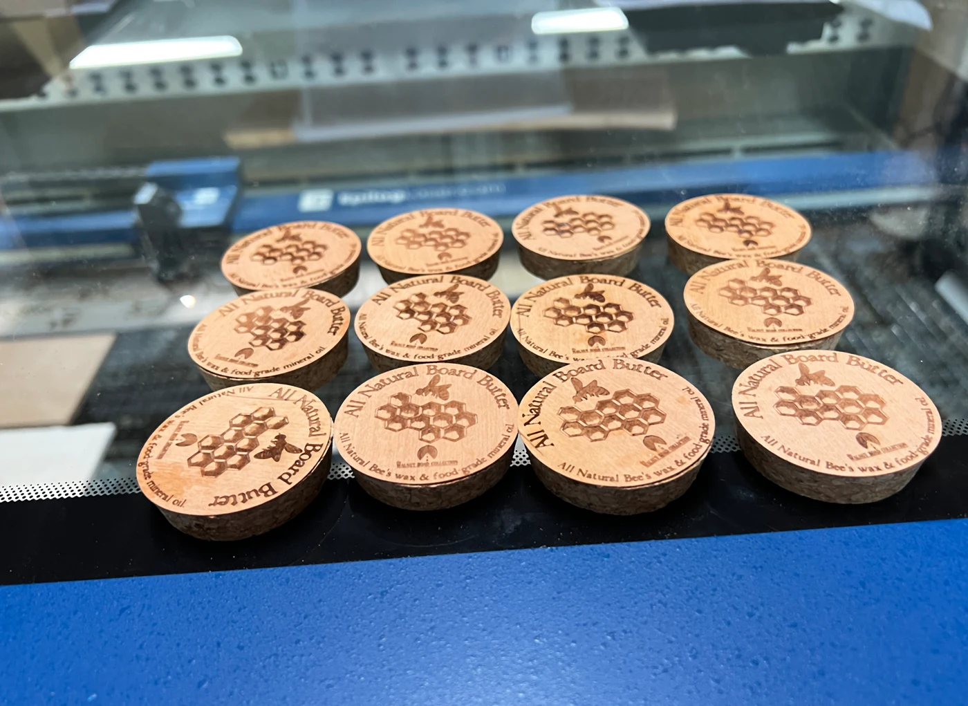 A batch of wooden lids with engraved branding inside the CO₂ laser
